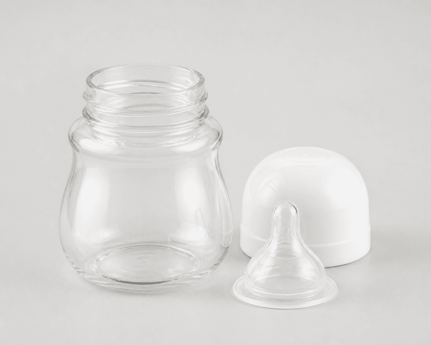 Wide-neck baby feeding bottle reference showing the clear bottle body, open wide threaded neck, white rounded cap, clear nipple, and detached parts on a neutral background