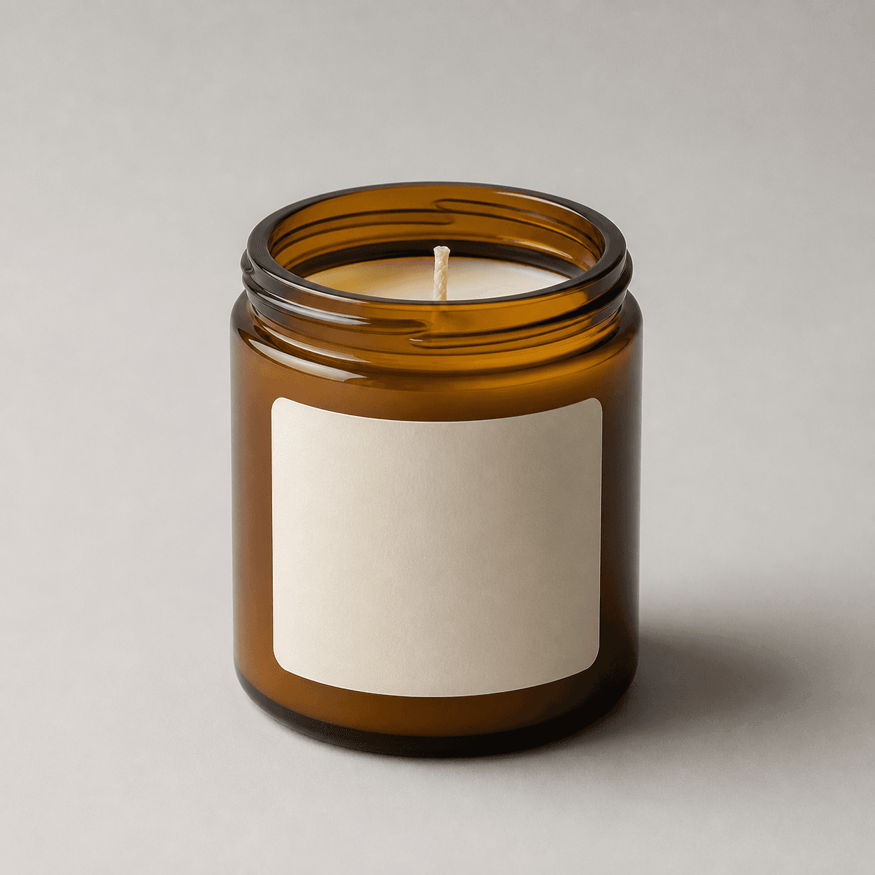 Minimal amber glass jar candle reference showing the front label, open rim, centered wick, pale wax, and complete base